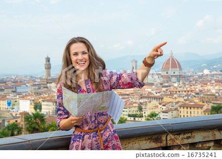 Smiling young woman with map pointing against panoramic view of Smiling young woman with map pointing against panoramic view of 16735241
