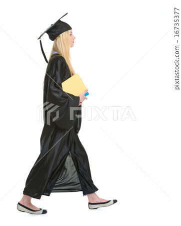 Young woman in graduation gown with books going sideways Young woman in graduation gown with books going sideways 16735377