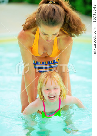 Mother and baby girl playing in swimming pool 16735548