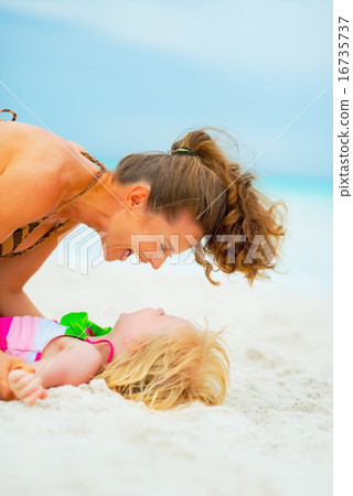 Laughing mother and baby girl playing on beach Laughing mother and baby girl playing on beach 16735737