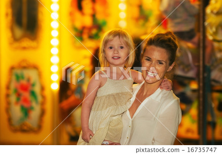 Portrait of happy mother and baby girl in front of carousel Portrait of happy mother and baby girl in front of carousel 16735747