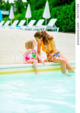 Happy mother and baby girl sitting at poolside Happy mother and baby girl sitting at poolside 16735784