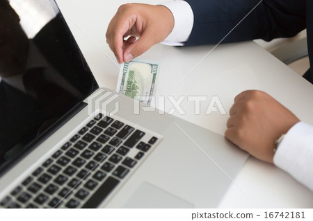 man in suit inserting dollar bill in the laptop man in suit inserting dollar bill in the laptop 16742181