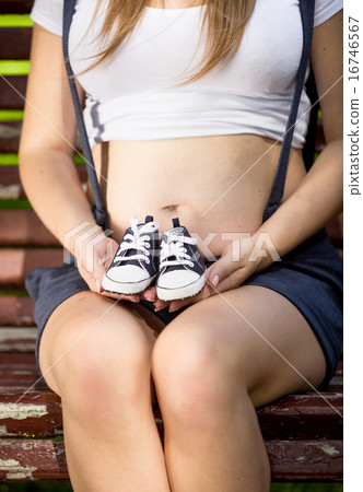 pregnant woman holding baby shoes on hands pregnant woman holding baby shoes on hands 16746567
