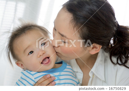 A baby kissed by a mother in the living room A baby kissed by a mother in the living room 16750829
