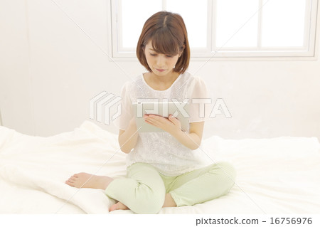 A woman watching a tablet on bed A woman watching a tablet on bed 16756976