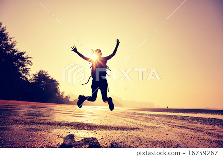 cheering young woman hiker jumping on sunrise beach 16759267