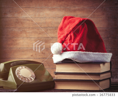 Santas hat over books near green dial phone 16775833