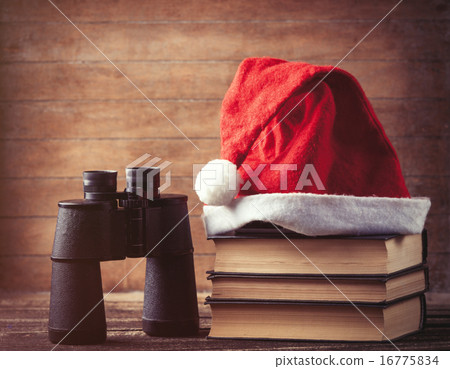 Santas hat over books near black binocular Santas hat over books near black binocular 16775834