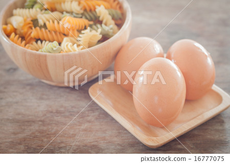 Fresh eggs on wooden plate with fusili Fresh eggs on wooden plate with fusili 16777075
