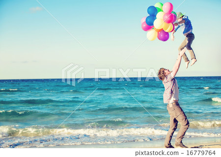 Happy father and son having great time on the beach in sunset light 16779764