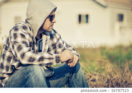 Portrait of a sad man in sunglasses sitting near the house Portrait of a sad man in sunglasses sitting near the house 16787523