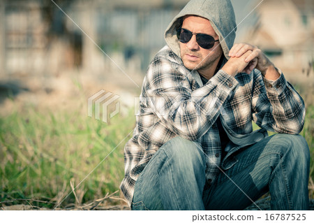 Portrait of a sad man in sunglasses sitting near the house Portrait of a sad man in sunglasses sitting near the house 16787525