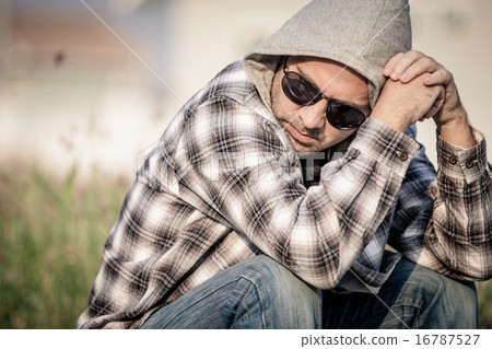 Portrait of a sad man in sunglasses sitting near the house Portrait of a sad man in sunglasses sitting near the house 16787527