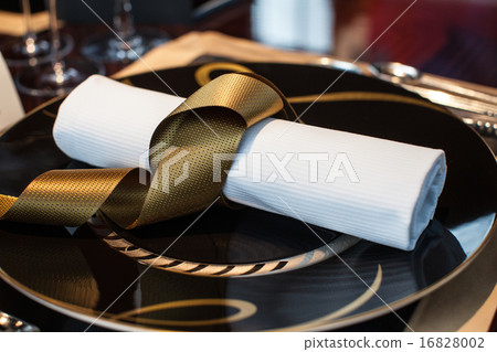 folded napkin laid on plate on the table 16828002