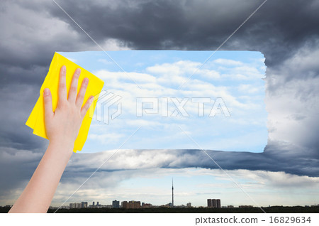 hand deletes rainy cloud over city by yellow cloth hand deletes rainy cloud over city by yellow cloth 16829634