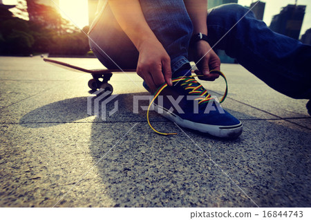 skateboarder tying shoelace at skate park skateboarder tying shoelace at skate park 16844743