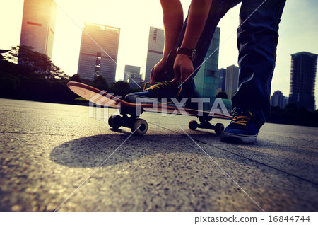 skateboarder tying shoelace at skate park skateboarder tying shoelace at skate park 16844744