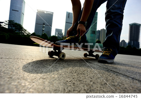 skateboarder tying shoelace at skate park skateboarder tying shoelace at skate park 16844745