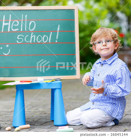 Cute little kid boy with glasses at blackboard practicing writin Cute little kid boy with glasses at blackboard practicing writin 16845144