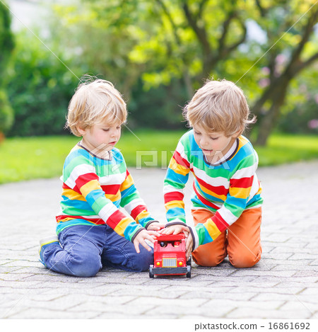 Two little friends playing with red school bus Two little friends playing with red school bus 16861692