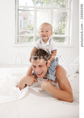 young father with his nine months old son on the bed at home young father with his nine months old son on the bed at home 16866896