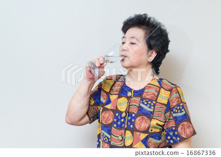 Asian senior woman with glass of water, on gray Asian senior woman with glass of water, on gray 16867336