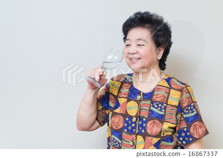 Asian senior woman with glass of water, on gray Asian senior woman with glass of water, on gray 16867337