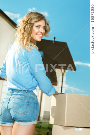 Young Woman Carrying Boxes In To New House 16871080
