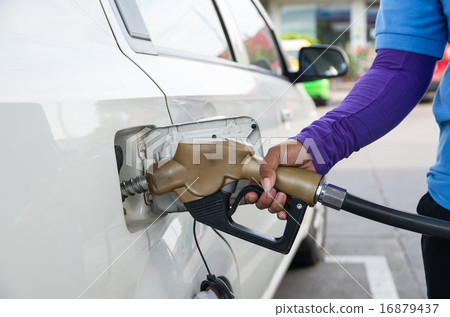 Hand hold Fuel nozzle to add fuel in car at filling station 16879437