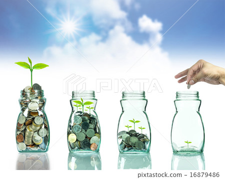 Hand putting mix coins and seed in clear blottle on blurred blue Hand putting mix coins and seed in clear blottle on blurred blue 16879486