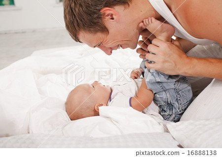 young father with his nine months old son on the bed at home 16888138