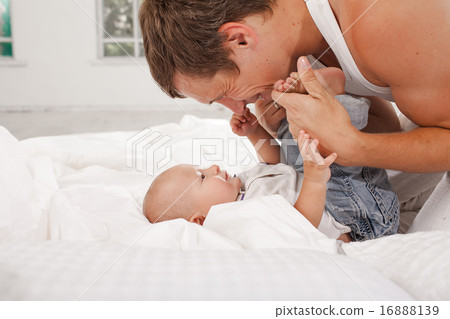 young father with his nine months old son on the bed at home 16888139