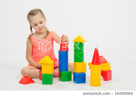 The girl puts on a tower house from cubes The girl puts on a tower house from cubes 16890068