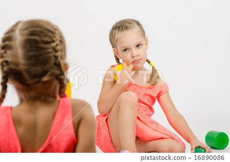 Girl misunderstanding looks at her sister while playing with toys Girl misunderstanding looks at her sister while playing with toys 16890086