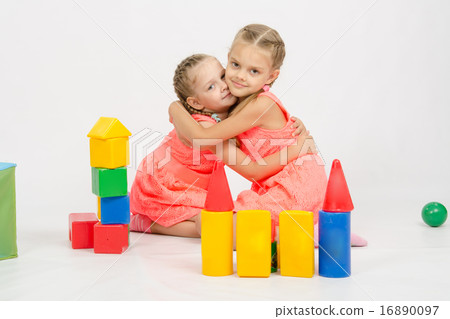 Happy two girls embrace building a castle out of blocks Happy two girls embrace building a castle out of blocks 16890097