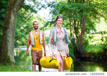 Man and woman carrying canoe to forest river 16890899
