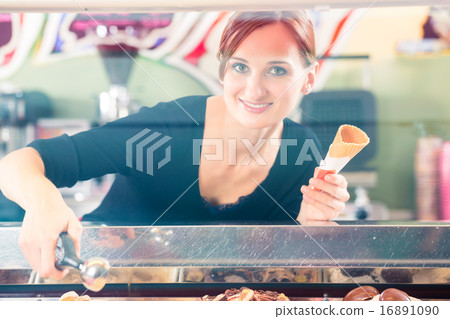 Sales girl portion s scoop  of ice cream to wafer 16891090