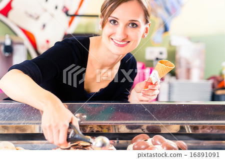 Sales girl portion s scoop  of ice cream to wafer 16891091
