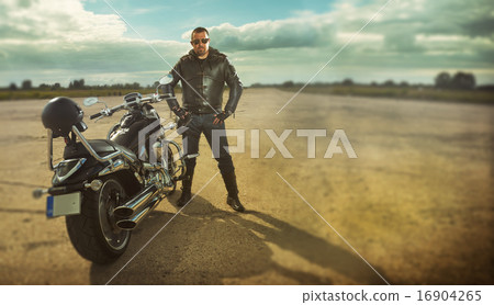 Biker standing by a motorcycle 16904265