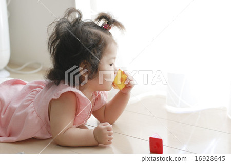 Baby putting a toy in her mouth 16928645