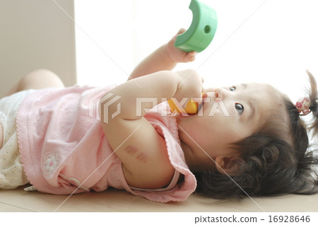 Baby putting a toy in her mouth 16928646