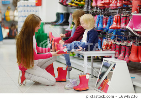 Mother and her two girls choosing new rain boots 16948236