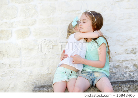 Two adorable little sisters laughing and hugging 16948400