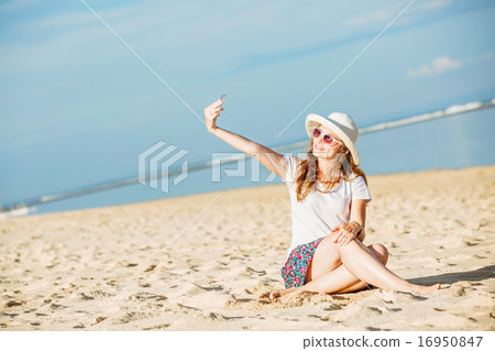 Beautiful young woman on the beach at sunny day taking selfie with phone Beautiful young woman on the beach at sunny day taking selfie with phone 16950847