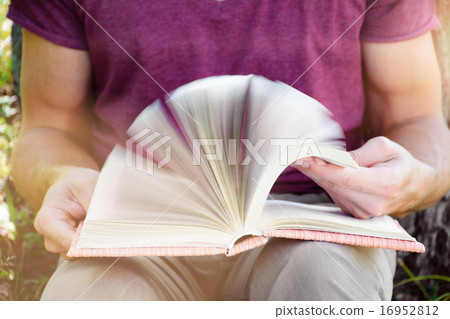 Young man is sitting and reading a book Young man is sitting and reading a book 16952812