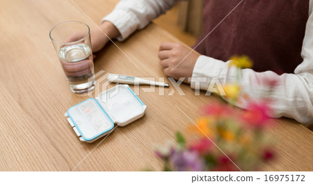 A woman picks up medicine and water. A woman picks up medicine and water. 16975172