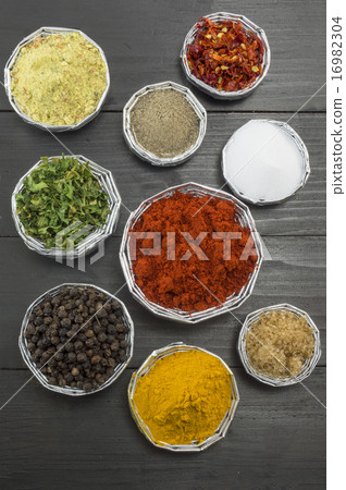 Various spices in shiny bowls on a wooden table 16982304