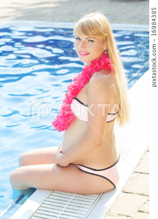 Pregnant girl is sitting near swimming pool 16984385