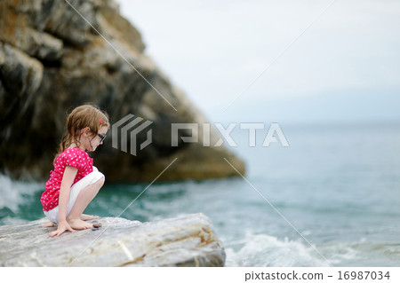 Adorable little girl sitting on a rock Adorable little girl sitting on a rock 16987034